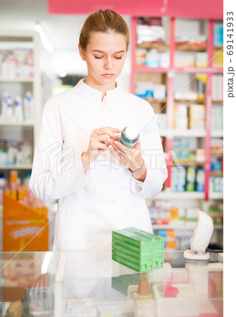 Young friendly pharmacist offering reliable medicine in pharmacy 69141933