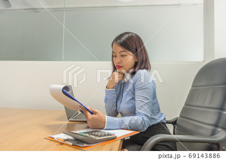 Portrait of Asian businesswoman holding financial reports and thinking 69143886