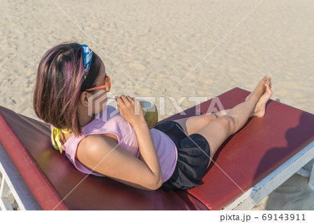 Asian woman drinking coconut juice lying on summer beach chair 69143911