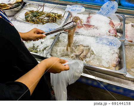 Woman picking frozen squid in seafood supermarket 69144158