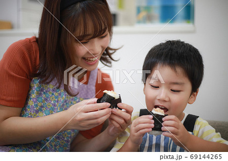 握ったおにぎりを食べる親子 69144265