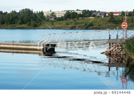 Summer village landscape. Wooden pier on the river and a lifebuoy. Summer village landscape. Wooden pier on the river and a lifebuoy. 69144446