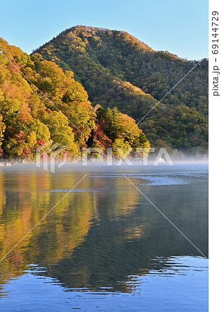 霧立つ中禅寺湖に千手ヶ浜の朝日当たる紅葉の森 霧立つ中禅寺湖に千手ヶ浜の朝日当たる紅葉の森 69144729
