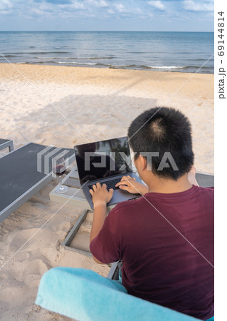 Asian man working with laptop by the beach 69144814