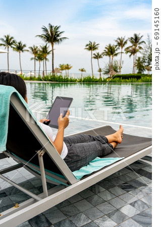 Closeup of Asian woman holding tablet at beautiful swimming pool Closeup of Asian woman holding tablet at beautiful swimming pool 69145160