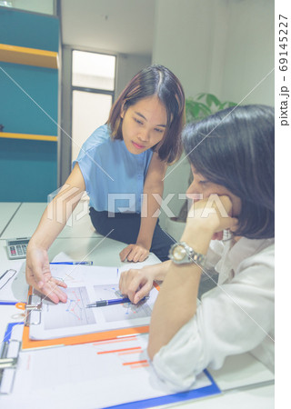 Vertical photo of Asian business people discuss about financial document 69145227