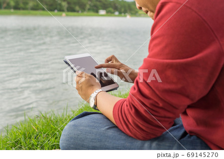 Man sitting in the park, using tablet 69145270