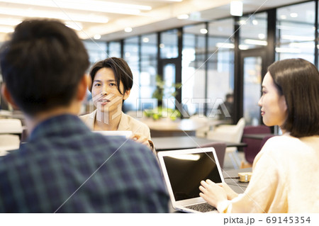 会社のフリースペースで資料を見せながら部下達に方針を説明する上司 会社のフリースペースで資料を見せながら部下達に方針を説明する上司 69145354