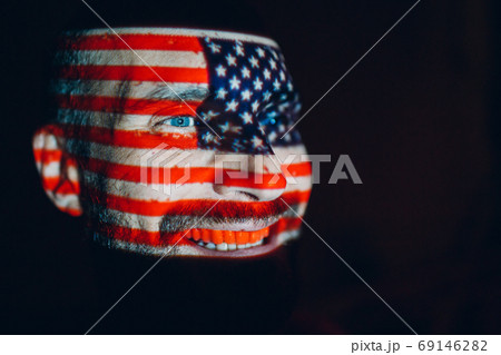 Adult man with USA flag on his face in the dark. 69146282