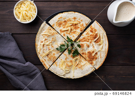 Pieces of quesadilla with mushrooms sour cream and cheese on a plate with parsley leaves. Wooden background copy space. 69146824