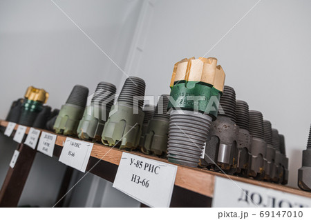 Drill Bits on shelving in stock. Oil equipment for drilling rig operation on oil platform in oil and gas industry. Brand new drilling bits. Written: drill bits Drill Bits on shelving in stock. Oil equipment for drilling rig operation on oil platform in oil and gas industry. Brand new drilling bits. Written: drill bits 69147010