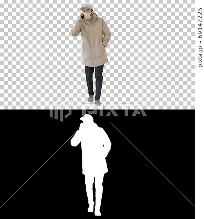 Casual man in outdoor clothes and medical mask walking and talki 69147225