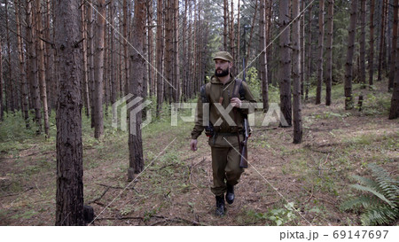 Hunting hunter men with gun walking through forest during hunting season. Man hunter outdoor in forest hunting alone. He has backpack and comfortable camouflage clothes. Hunting hunter men with gun walking through forest during hunting season. Man hunter outdoor in forest hunting alone. He has backpack and comfortable camouflage clothes. 69147697