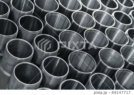 Pattern of metal cylinders stand on table at factory. Steel products to automotive industry. Billet obtained on lathe from steel and cast iron. Circular precision steel parts arranged in rows 69147717
