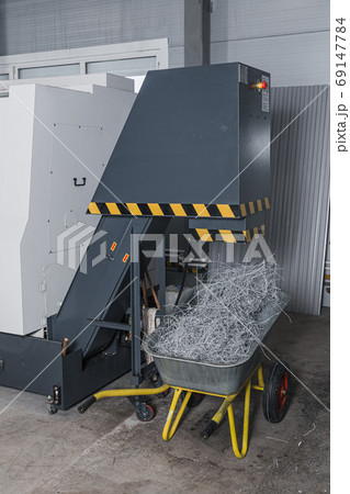 Twisted metal scrap from modern lathe milling cnc machine in garden trolley. Steel scrap materials recycling. Chip waste after machining metal parts on cnc lathe. Heap of CNC metal shavings. 69147784