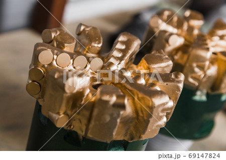 Brand new golden color PDC Polycrystalline Diamond Compact drilling bit. Drill bits on shelving in stock. Oil drilling equipment for drilling rig operation on oil platform in oil and gas industry. Brand new golden color PDC Polycrystalline Diamond Compact drilling bit. Drill bits on shelving in stock. Oil drilling equipment for drilling rig operation on oil platform in oil and gas industry. 69147824