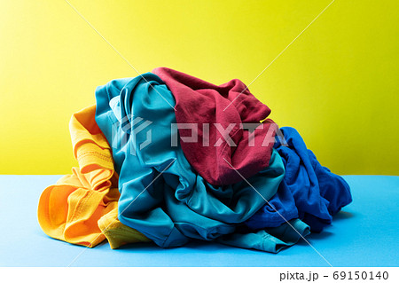 Pile of colorful laundry clothes on blue table Yellow light back Pile of colorful laundry clothes on blue table Yellow light back 69150140