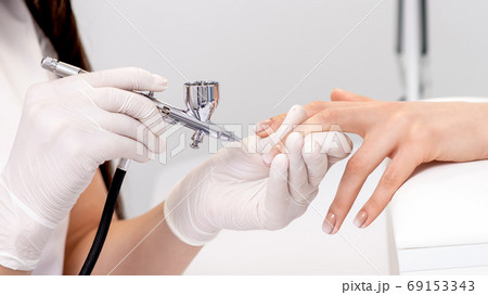 Manicure master using airbrush. 69153343