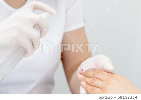 Manicurist is appies spray on client hand. Manicurist is appies spray on client hand. 69153354
