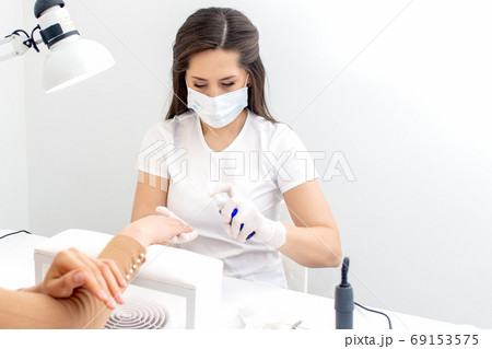 Manicurist is appies spray on client hand. Manicurist is appies spray on client hand. 69153575