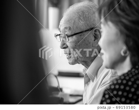 A very old asian man talking happily while surrounded by his family A very old asian man talking happily while surrounded by his family 69153580