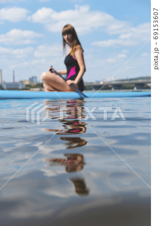 A beautiful woman is engaged in summer active sports on the river on a SUP board A beautiful woman is engaged in summer active sports on the river on a SUP board 69153607