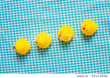 Row of yellow rubber ducks on green check pattern fabric background. Business leadership concept Row of yellow rubber ducks on green check pattern fabric background. Business leadership concept 69153608
