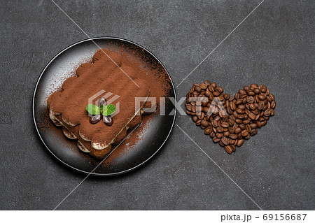 portion of Classic tiramisu dessert on ceramic plate and heart shaped coffee beans on concrete background 69156687