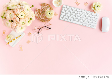 Stylized, pink women's home office desk. Workspace with computer, bouquet ranunculus and roses, clipboard on pink background. Flat lay. Top view. Stylized, pink women's home office desk. Workspace with computer, bouquet ranunculus and roses, clipboard on pink background. Flat lay. Top view. 69158470