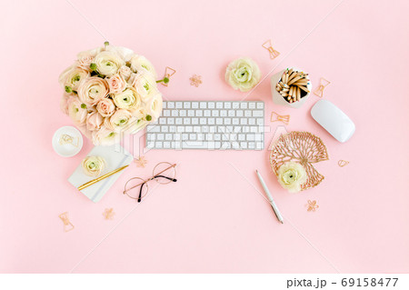 Stylized, pink women's home office desk. Workspace with computer, bouquet ranunculus and roses, clipboard on pink background. Flat lay. Top view. Stylized, pink women's home office desk. Workspace with computer, bouquet ranunculus and roses, clipboard on pink background. Flat lay. Top view. 69158477