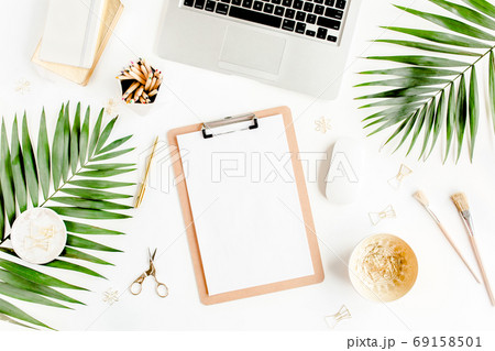 Flat lay home office desk. Female workspace with computer, clipboard, tropical palm leaves, accessories on white background. Top view. Flat lay home office desk. Female workspace with computer, clipboard, tropical palm leaves, accessories on white background. Top view. 69158501