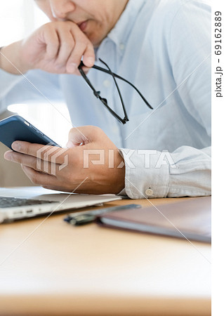パソコンとスマホを見るミドル男性 パソコンとスマホを見るミドル男性 69162889