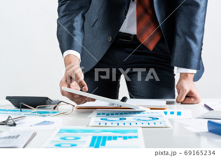 Businessman standing near office desk Businessman standing near office desk 69165234