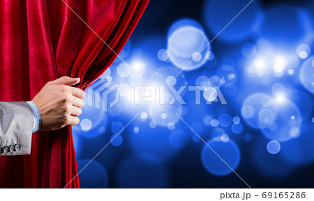 Bokeh lights behind drapery curtain and hand opening it 69165286
