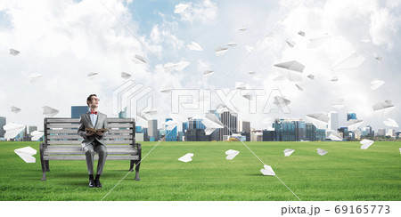 Young businessman or student studying the science and paper planes flying around 69165773