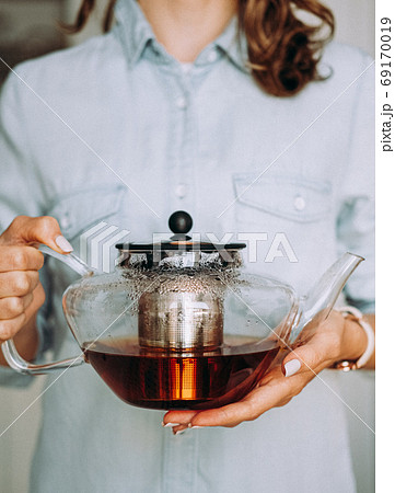 Young woman holding a glass teapot Young woman holding a glass teapot 69170019