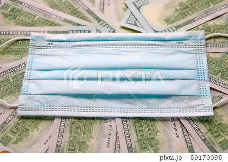 Medical mask on dollars as a symbol of increasing prices for protecting the respiratory tract from the virus. There is a place for copyspace. Medical mask on dollars as a symbol of increasing prices for protecting the respiratory tract from the virus. There is a place for copyspace. 69170096