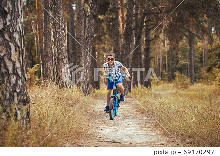 Happy kid cyclist rides in the forest on a bike. 69170297