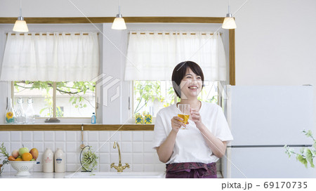 キッチンでグラスを持った笑顔の女性 キッチンでグラスを持った笑顔の女性 69170735