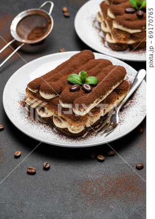 Two portions of Classic tiramisu dessert on ceramic plate on concrete background Two portions of Classic tiramisu dessert on ceramic plate on concrete background 69170765