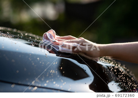 hand wiping water on black car 69172360