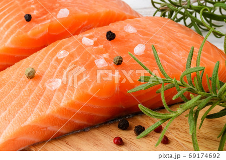 Close-up of two raw chilled salmon fillets with pepper grains, salt and fresh rosemary. 69174692