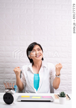 Happy successful woman with raised hands sitting at home office 69177779