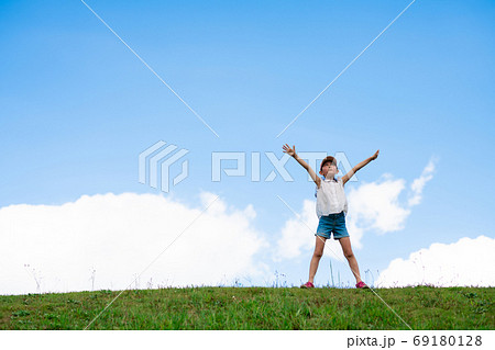 青空の下で両手を広げる子供の写真素材