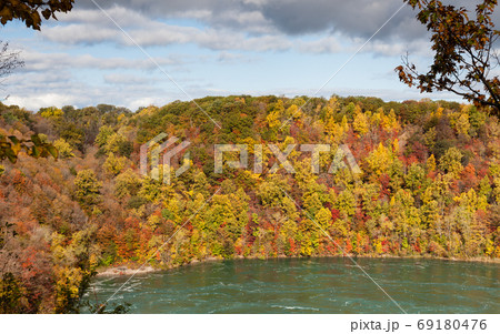 Niagara Whirlpool. The view across Niagara Whirlpool located on the Canadian and American border. In the background can be seen the colorful foliage of trees during the fall. 69180476