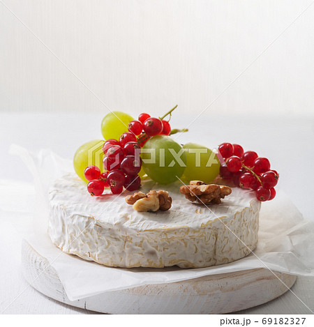 Camembert cheese with fruits, nuts and berries on a white background 69182327