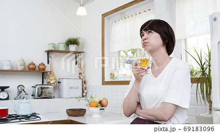 キッチンでグラスを持った怒った表情の女性 キッチンでグラスを持った怒った表情の女性 69183096
