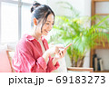 ソファでくつろぎながらスマホを操作する女性。 69183273