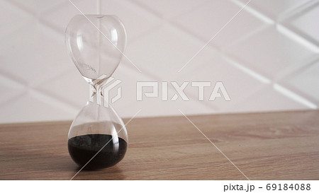 Crystal hourglass with black sand on wooden table 69184088