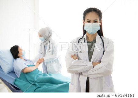 Asian female doctor wearing protective mask and Asian female muslim doctor taking care of patient Asian female doctor wearing protective mask and Asian female muslim doctor taking care of patient 69184161